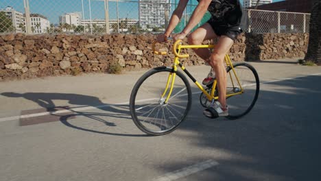 man on a yellow fixed-gear bicycle on a city street.