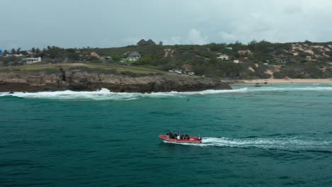 Panning-drone-shot-above-a-boat-and-surf-lineup-in-Tofo,-Mozambique