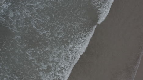 Ocean-lapping-on-beach-shot-with-drone-in-4K-spiral