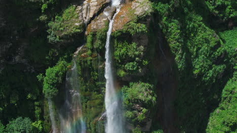 a breathtaking drone shot capturing a waterfall in nepal, cascading peacefully over a cliff amidst lush greenery