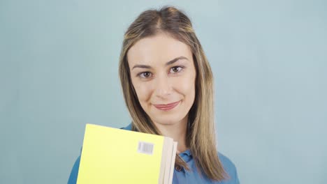 una joven estudiante con libros y mirando a la cámara.