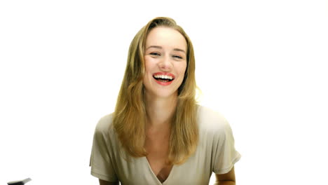 A-close-up-of-a-woman-doing-a-full-body-laugh,-and-brushing-her-hair-out-of-her-face,-on-a-seamless-white-studio-background