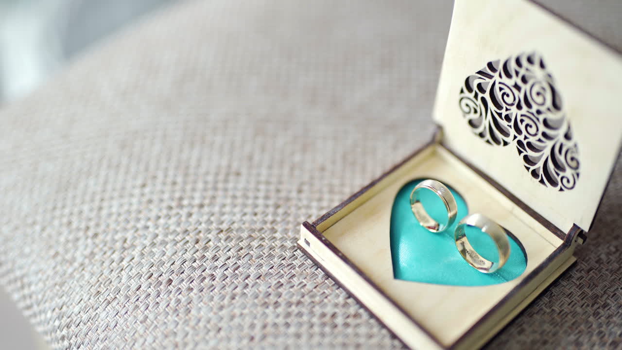 Anillos de boda dorados en una caja de madera decorativa con forma de corazón
