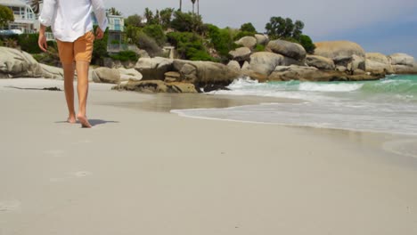 Rear-view-of-man-walking-barefoot-on-the-beach-on-a-sunny-day-4k-