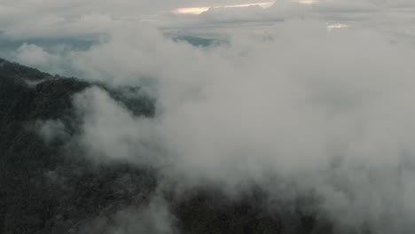 drone aéreo volando alto a través de las nubes sobre la montaña y el bosque