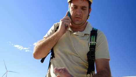 ingeniero masculino hablando por teléfono móvil en el parque eólico 4k