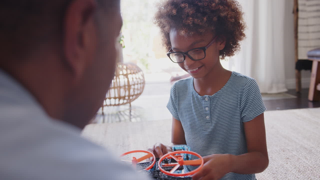 Over shoulder view of pre-teen girl constructing a toy with her grandfather, close up