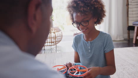 Over-shoulder-view-of-pre-teen-girl-constructing-a-toy-with-her-grandfather,-close-up