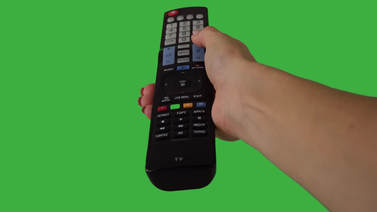 녹색 배경 위에서 원격 제어 버튼을 손으로 러