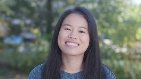 young asian american woman removes face mask and smiles, close up