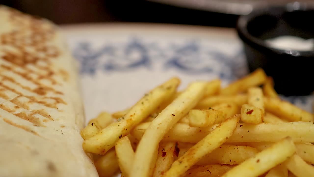 Close-up of toasted tortilla wraps served with crispy seasoned fries and dipping sauce