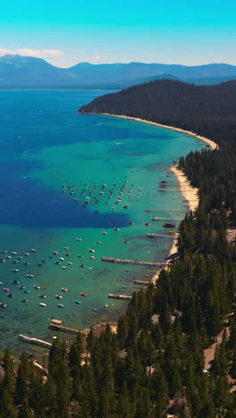 turquoise waters of amazingly beautiful lake tahoe with wooded shore. the sierra nevada mountains at backdrop. aerial view. vertical video