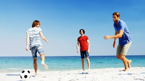 friends playing football at beach