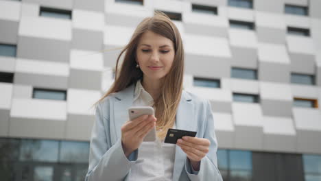 mujer joven sonriente cliente con tarjeta de crédito y teléfono inteligente feliz compradora femenina usando instantáneo