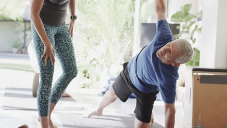 focused caucasian senior man practicing pilates with female coach, unaltered, in slow motion