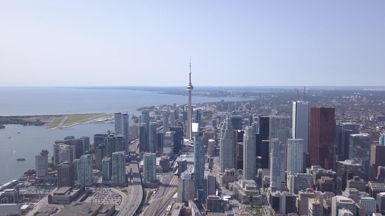 Dynamisk vidvinkelbild från luften av Torontos stadssiluett och Ontariosjön under en varm, ljus, solig dag. Kamerarörelse: Dolly framåt och jib uppåt.