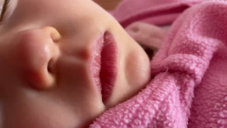 Eine-Nahaufnahme-Eines-Babys,-Das-Ein-Rosa-Wolltuch-Trägt-Und-Auf-Dem-Bett-Schläft