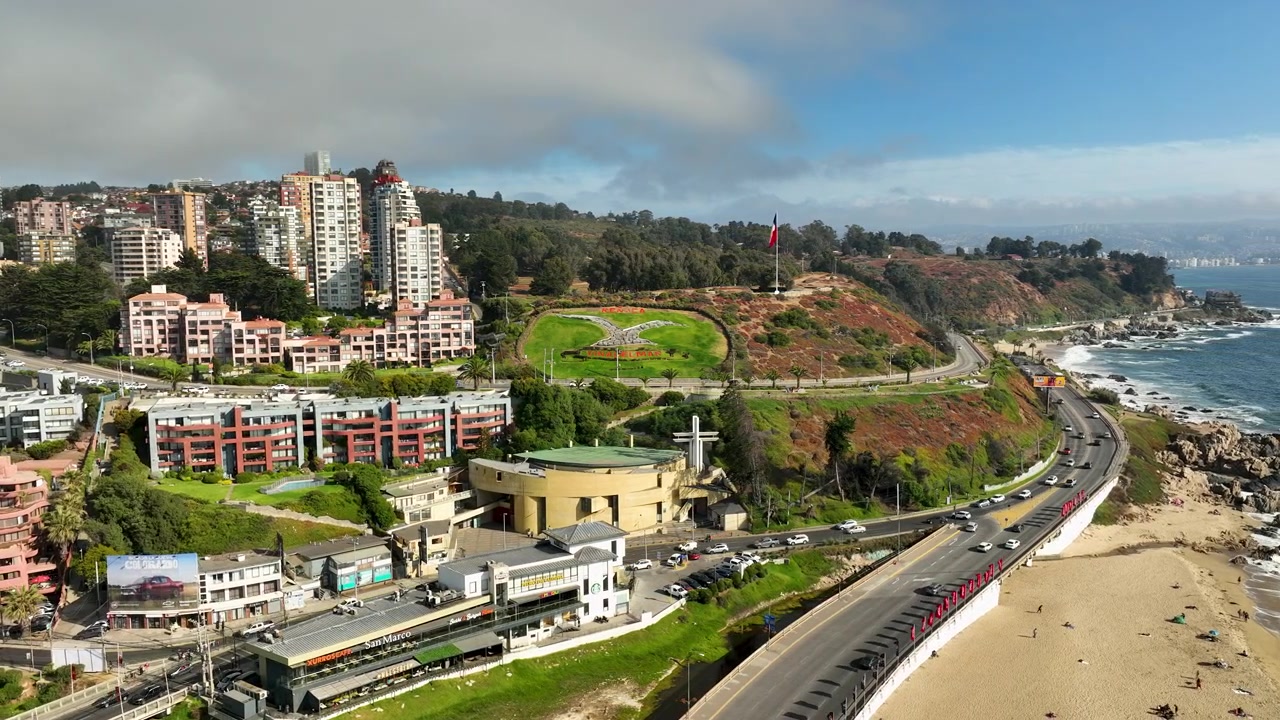 Vista aerea dall'alto con drone dell'iconico design a fiore di gabbiano su una collina accanto al traffico dell'autostrada costiera e alla spiaggia oceanica a Reñaca, Cile.