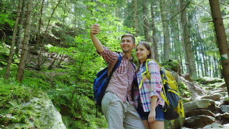 an attractive couple of tourists are photographed in the forest selfie with backpacks on a hike 4k v