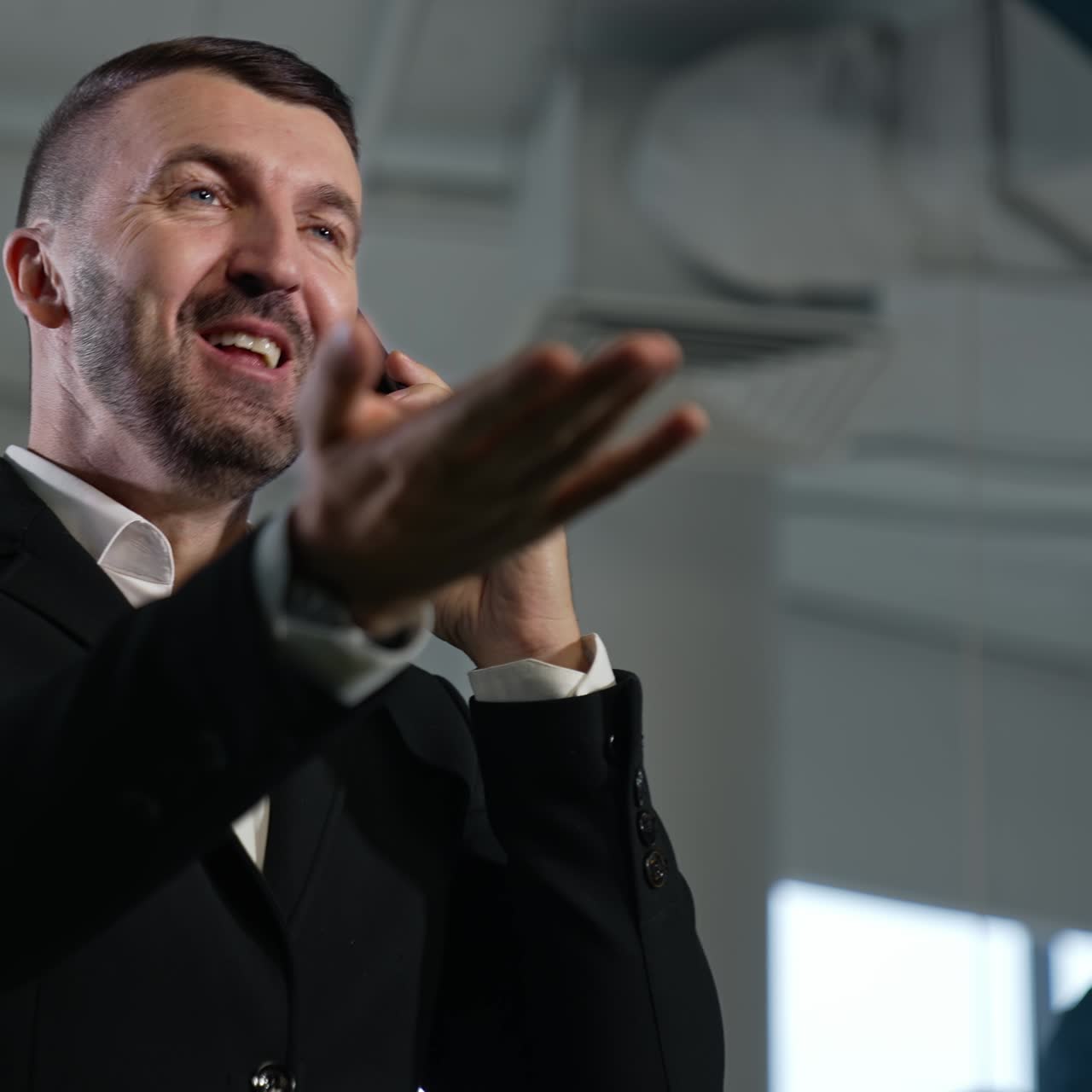 Male entrepreneur speaking on the phone. Happy expression on man's face during conversation. Low angle view