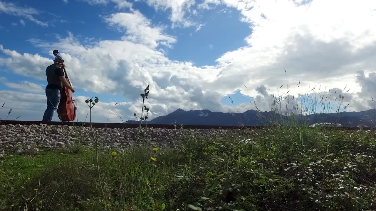 철도 트랙 에서 더블 베이스 를 연주 하는 음악가