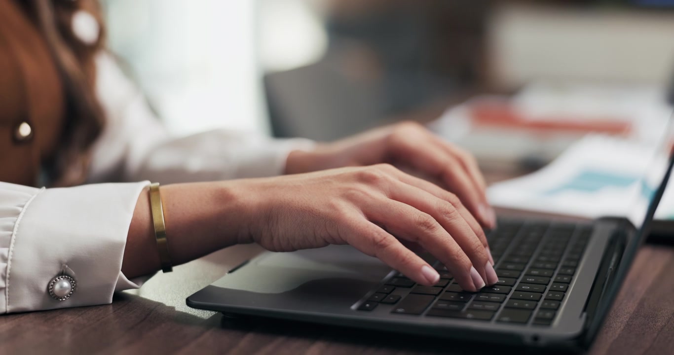 Close-up of a Woman Typing on a Laptop in an Office
