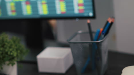 Telephone-on-office-desk-and-monitor-showing-stock-exchange-values,-close-up