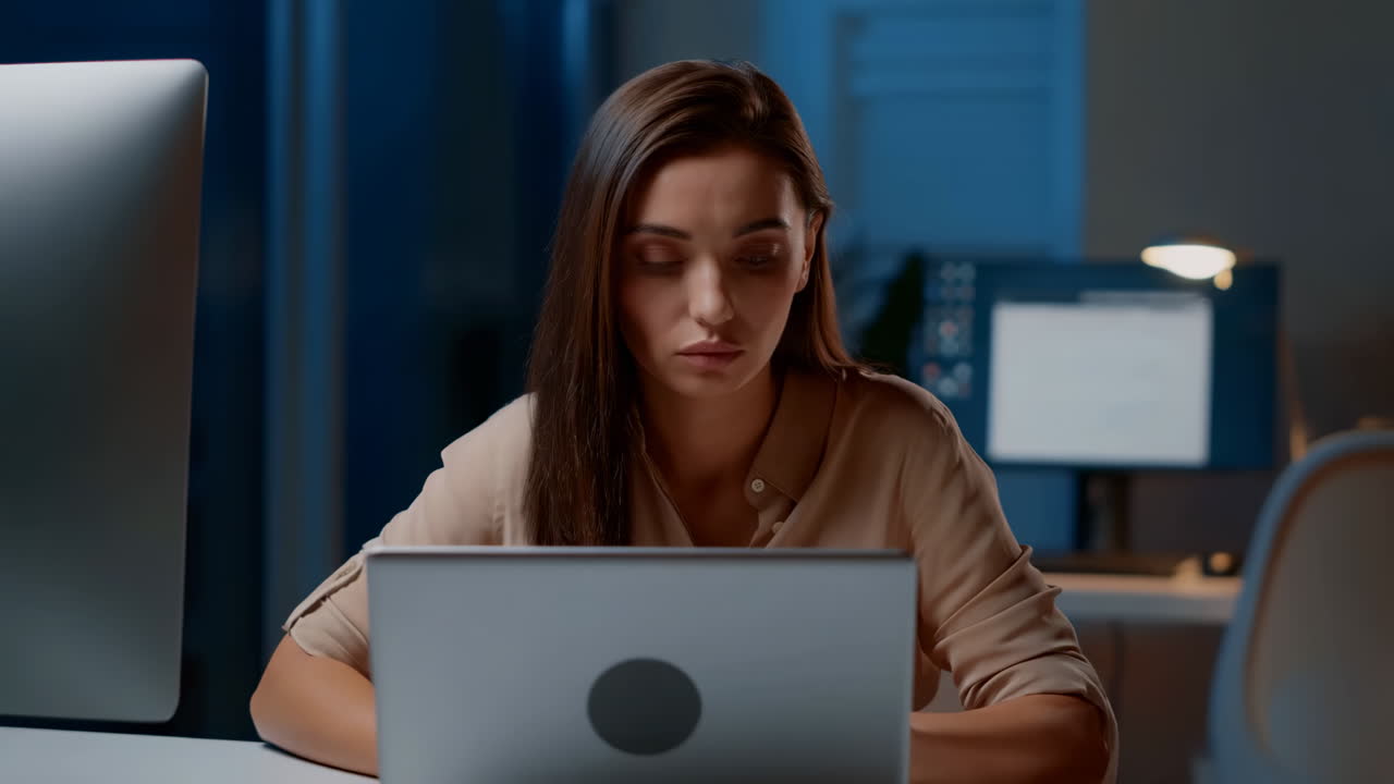 Donna professionista che lavora fino a tardi al portatile in ufficio scuro