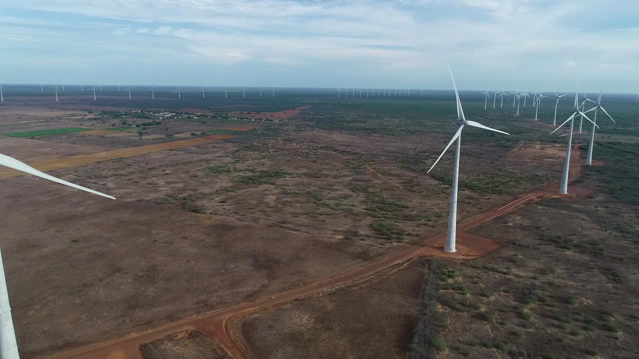 Drone footage of a wind farm operating in the Brazilian hinterland, forward movement and side tracking
