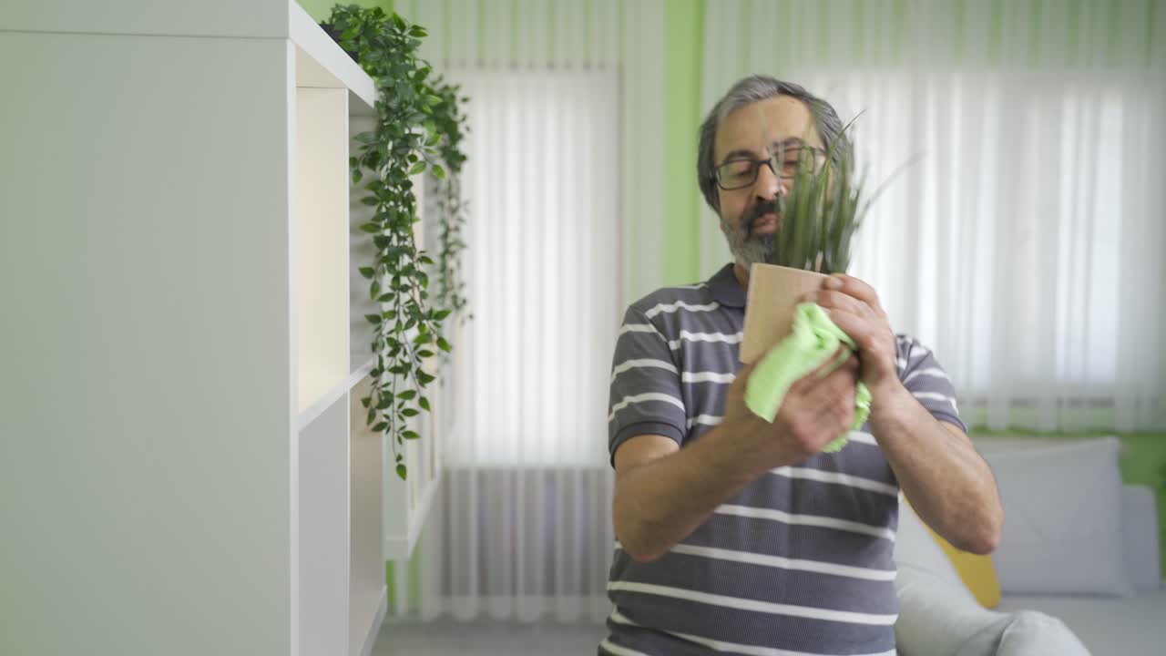 즐거운 성숙한 남자가 집을 청소하고 있습니다.