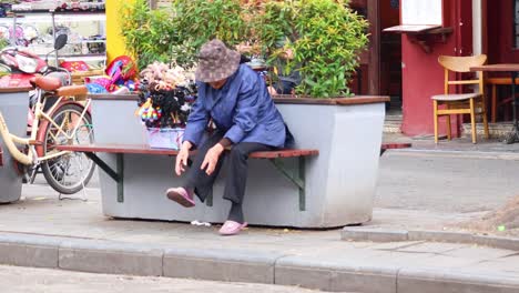 woman rests on bench beside bicycles and flowers