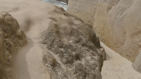 camine lentamente por el 'camino' en una enorme roca arenisca para revelar una hermosa playa aislada y las olas del océano pacífico sur - vía de la playa del túnel, dunedin