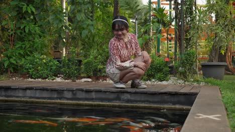 joyful indonesian girl playing with koi fish in a pond