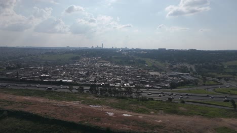 in this 4k aerial footage, a push-in shot approaches the bustling city of johannesburg, framing a busy highway and township, providing a dynamic glimpse into urban energy and daily life