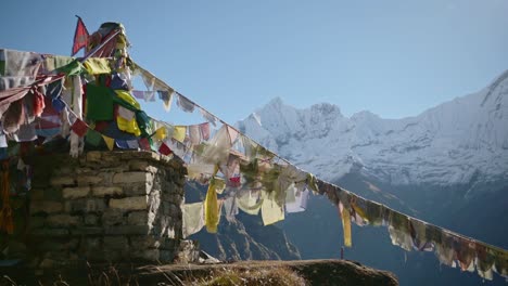 banderas de oración budista y montañas de nepal, banderas de oración tibetana en el cielo azul en un día soleado en los nevados himalayas en la región de annapurna, banderas emblemáticas de budismo coloridas en la naturaleza
