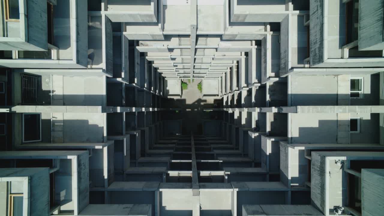 Telecamera aerea che rivela e amplia la vista di un pozzo di luce verticale in un cortile urbano, mettendo in risalto le fioriere.
