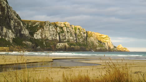 Establish-stunning-huge-mountain-rocks-in-Purakaunui-beach,-New-Zealand,-sunset