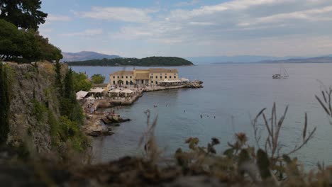 Toma-Estática-De-Establecimiento-De-Un-Antiguo-Hotel-Griego-En-El-Borde-De-La-Costa-Rocosa-En-Corfú,-Grecia