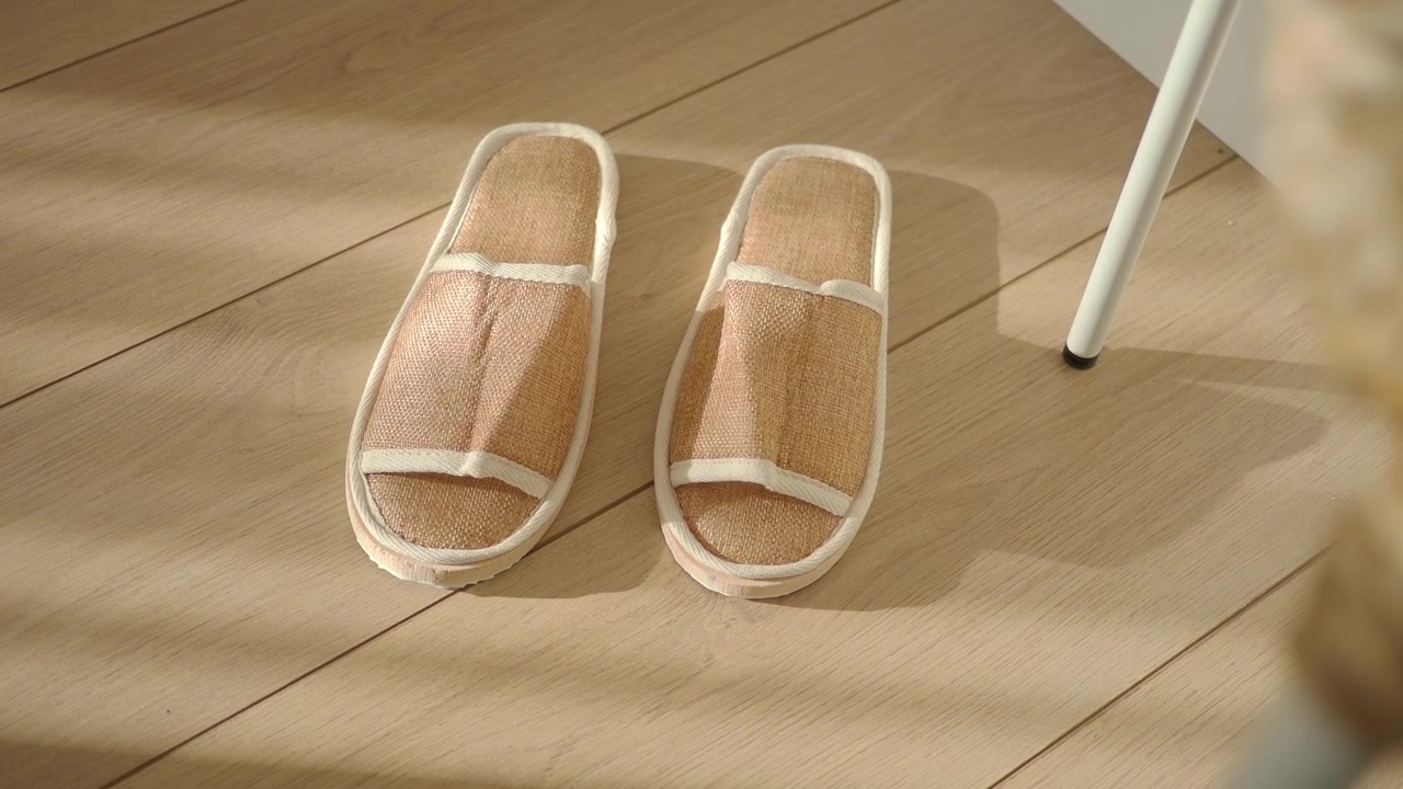 Paio di pantofole in lino naturale su pavimento in legno