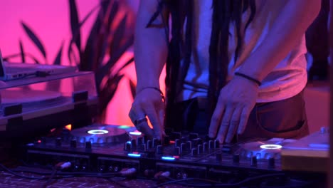 dj with dreadlocks remixing music using turntable during live performance, filmed as close up on lower body