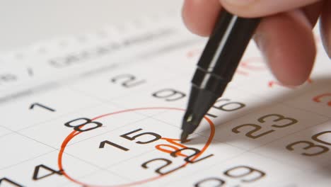 firmar un día de pago en un calendario con una pluma roja