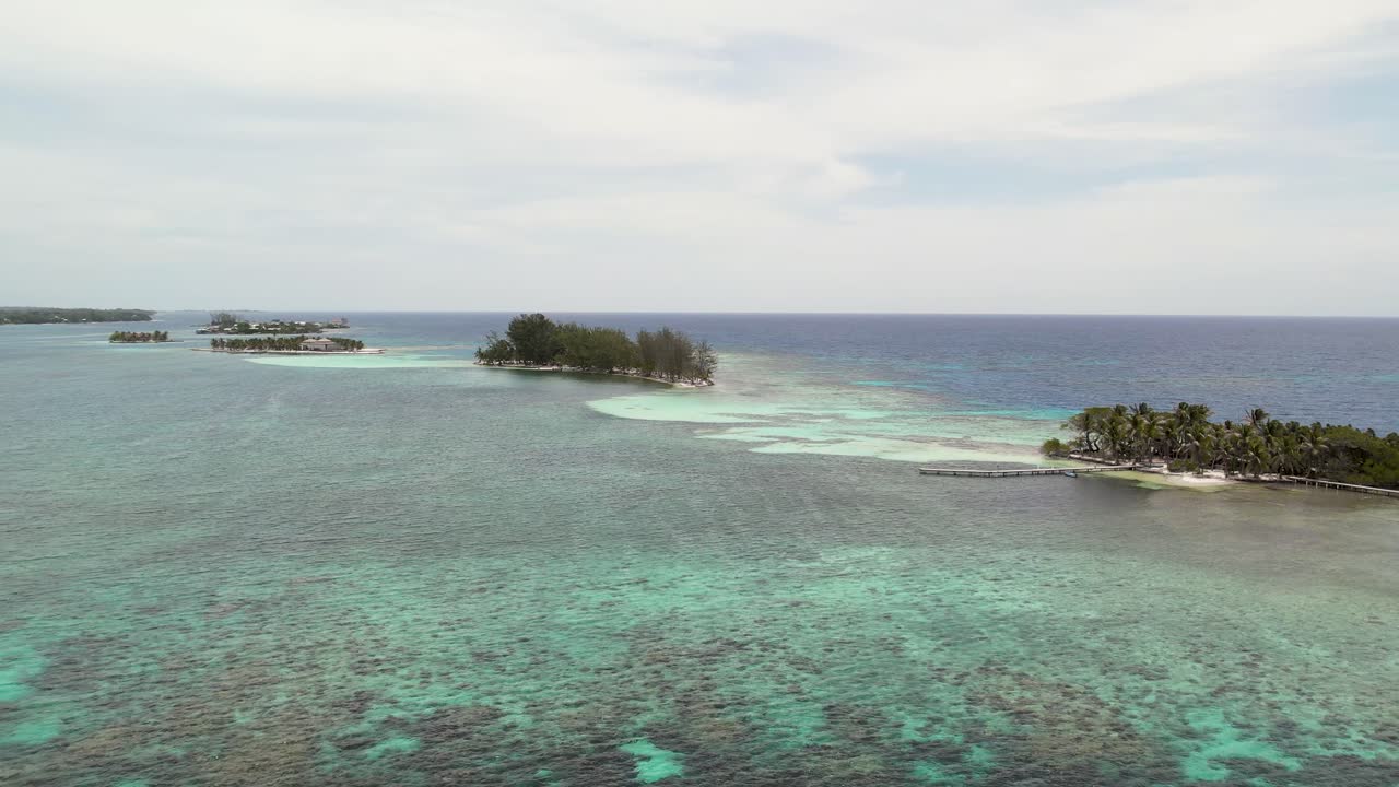 Spiaggia sabbiosa su isola tropicale circondata da barriera corallina, vista aerea.