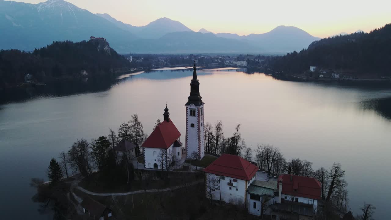 Il campanile si erge dall'isola nel lago di Bled mentre le montagne sfumano nel crepuscolo
