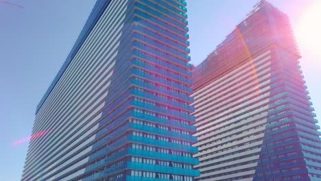 shot of reflections of sun, clouds and sky on glass windows of city skyscraper.