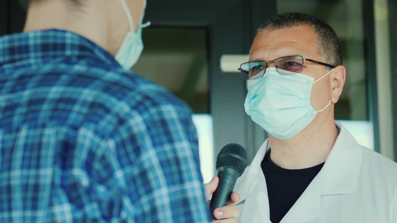 Un giornalista con una mascherina protettiva intervista un medico all'ingresso dell'ospedale.