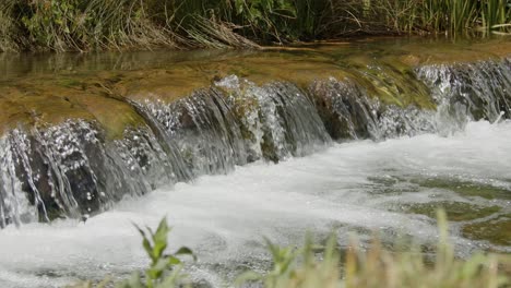 Bubbling-stream-waterfall-flowing-in-slow-motion-near-Seton-Castle,-East-Lothian,-Scotland,-UK