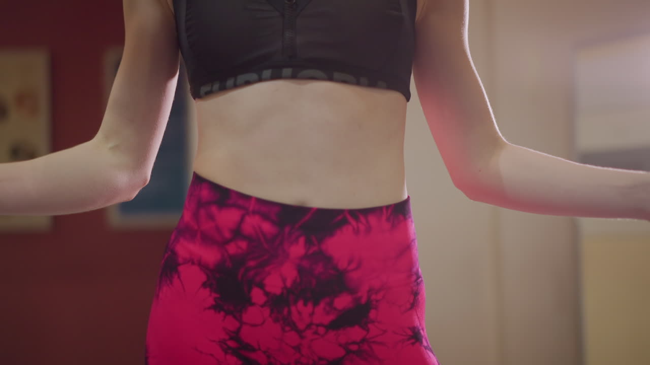 asian woman midsection with jump rope, vivid pink patterned leggings and black sports bra, closeup on grip and hip movement, focus on core engagement and steady tempo, fashionforward athleisure vibe
