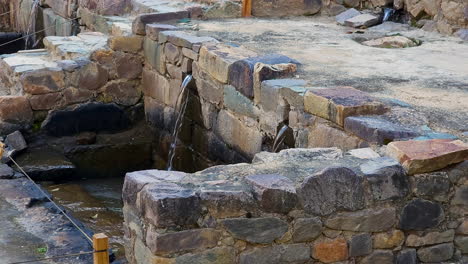 a cinematic pan shot captures the ancient inca water fountains and intricate stone channels of the ollantaytambo archaeological park, showcasing their historic and cultural significance