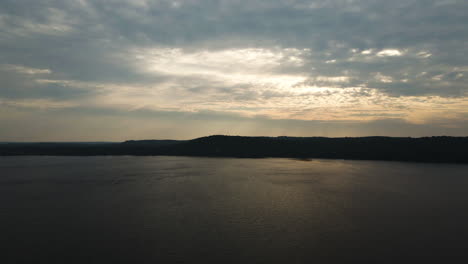 panorámica aérea a través del cielo de nubes de tormenta perforado por rayos de luz de luz dorada en el lago maple ontario