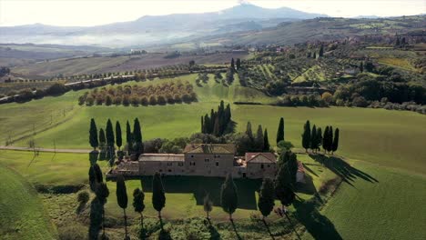 amazing landscape scenery of tuscany in italy - farmhouse, cypress trees along white road  - aerial view